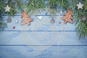 Christmas or New Year flat lay: pine branches with some wooden decorations on the blue boards