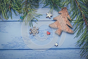 Christmas or New Year flat lay: pine branches  wooden Christmas tree and some decorations on the blue boards