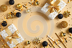 Christmas or New Year frame composition. Christmas decorations in gold and black colors and gift boxes on golden background with