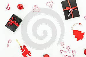 Christmas, New year frame composition. Gift box, red decoration, candy canes and confetti on white background. Flat lay, top view