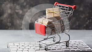 Christmas or New year gift paper box gold ribbon in a small shopping cart on a laptop keyboard