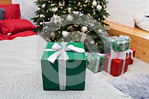 Christmas, New Year green gift box on the bed. Traditional winter holidays gifts packaging creative concept. Modern interior