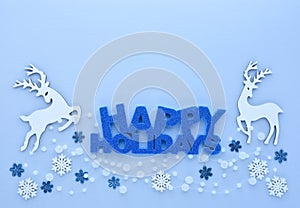 Christmas or New Year greeting card. Greeting `Happy Holidays`, deers and snowflakes on pastel blue background.