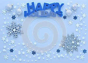 Christmas or New Year greeting card. Greeting `Happy Holidays` and snowflakes on pastel blue background.