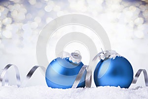 Christmas and New Year greeting card. Holiday ornament, winter decoration. Blue christmas balls with silver ribbon in snow over