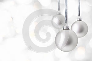 Christmas and New Year greeting card. Holiday ornament, winter decoration. Silver christmas balls hanging on ribbon over bokeh
