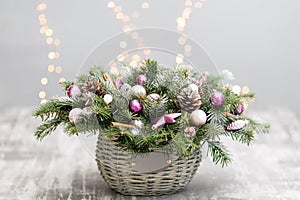 Christmas or New Year greeting card with a wicker basket with pine cones, fir branches, decorative balls on old wooden