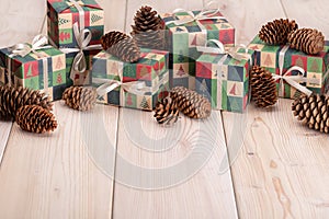 Christmas and New Year greetings. Pine cones and festive boxes with gifts on a light wooden background.