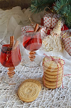Christmas and new year holiday celebration concept background. Glass of mulled wine with spices, homemade cookie, xmas tree decora