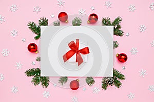 Christmas, New Year holiday layout. White gift box with red bow in frame of natural fir tree branches and decorations on