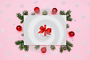 Christmas, New Year holiday layout. White gift box with red bow in frame of natural fir tree branches and decorations on