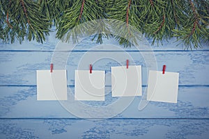 Christmas or New Year mock up: some pine branches and white stickers with red clothespins on the blue boards