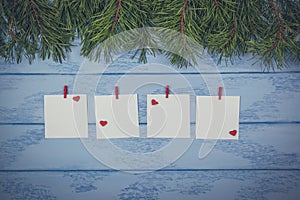 Christmas or New Year mock up: some pine branches and white stickers with small red hearts and clothespins on the blue boards