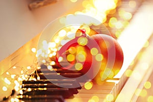 Christmas and New Year music. Piano with fairy lights and festive ball, bokeh effect