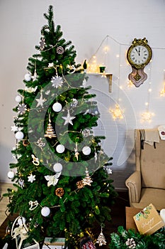 Christmas and New Year photo studio, green tree, soft chair, garlands stars, clock on a white wall (4).