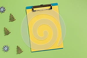 Christmas or New Year planning concept. Clipboard with yellow sheet, on green background