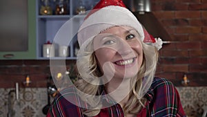 Christmas or New Year, portrait of a young happy woman in a Santa hat. The woman says Santa's phrase Ho ho ho