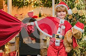 For Christmas and New Year posters. Santa child. Santa helper holding a red bag with presents. Little Santa Claus