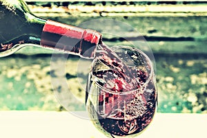 Pouring wine. Red wine in a glass. Sommelier wine into the glass on a blue background old.