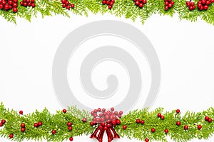 Top view of spruce branches, pine cones, red berries and bell on white background.