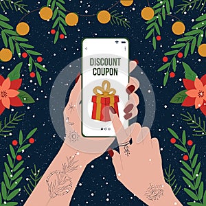 Christmas and New Year Shopping. Woman`s hands in a tattoo holding smart phone with gift box coupon icon