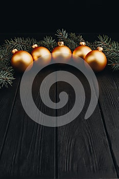 Christmas or New Year toy decorations golden balls and fur tree branch rustic on wooden background, top view, copy space