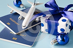 Christmas or New Year travel concept. Toy airplane with passports and gift box on blue background