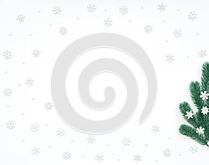 Christmas, New Year or winter white background with fir tree branches, small white snowflakes, beads. Xmas and Happy New Year