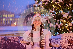 Christmas. New Year. Young cheerful girl in a red cap at the par