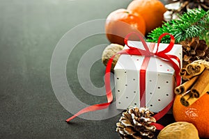 Christmas New Years gift box with red ribbon bow. Tangerines pine cones walnuts fir tree branches. Greeting card template
