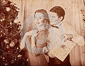 Christmas nostalgy couple on party near Xmas tree take gift box.