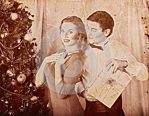 Christmas nostalgy couple on party near Xmas tree take gift box. photo