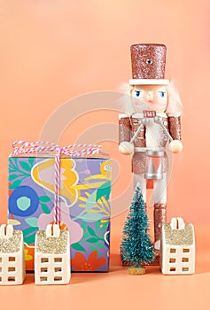 Christmas nutcracker ornaments and gifts against a modern coral background.