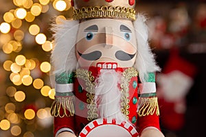 Christmas nutcracker wooden figure, toy soldier decoration with tree lights bokeh.