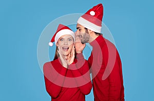 Christmas Offer. Young man whispering secret to his surprised wife