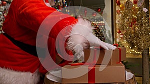 Christmas old bearded Santa Claus packing presents gift boxes in sack bag in his residence