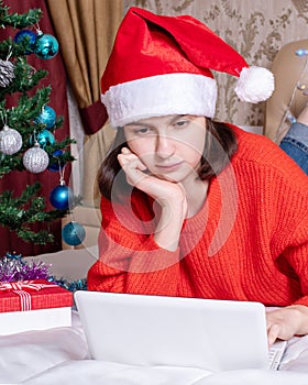 Christmas online greeting. girl in santa claus hat talking, using laptop for video calls to friends and parents