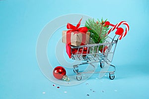 Christmas online shopping concept. Shopping cart with gifts, Christmas decor, Christmas tree on a blue background. background. 3d