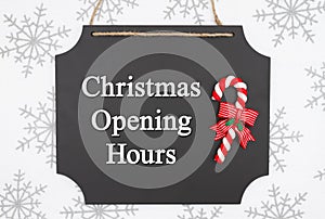 Christmas opening hours message on hanging chalkboard with a candy cane