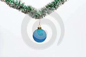 Christmas ornament concept. Ball with glamorous ornaments hang on shimmering green tinsel. Decoration for Christmas tree