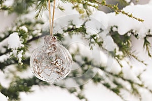 Christmas ornament on snowy pine tree branch