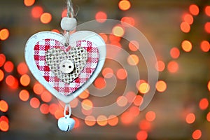 Christmas ornament: Wooden heart with jingle bell against Christmas lights