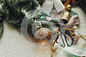 Christmas ornaments aesthetics. Stylish christmas vintage baubles, ribbons, brass bells and scissors on cozy white chair. Merry