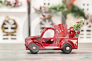 christmas ornaments and car toy with tree presents on wooden house background