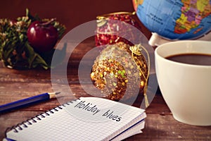 Christmas ornaments, cup of coffee, globe and text holidays blue