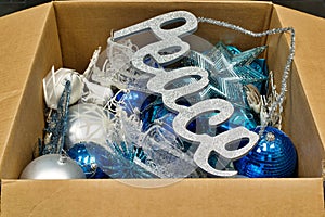 Christmas ornaments and a peace sign decoration in an open cardboard box.