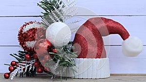 Christmas ornaments pine and bulbs next to glittered Santa hat on a white background with copy space