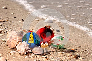 Christmas ornaments and shells on a sandy beach with a wave along the Gulf of Mexico for the holiday.