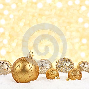 Christmas ornaments in snow with twinkling gold background