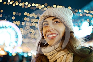 Christmas outdoor portrait woman at everning, festive Christmas fair on background